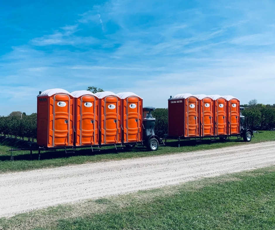 a trailer with several orange portable toilets on the back of it.