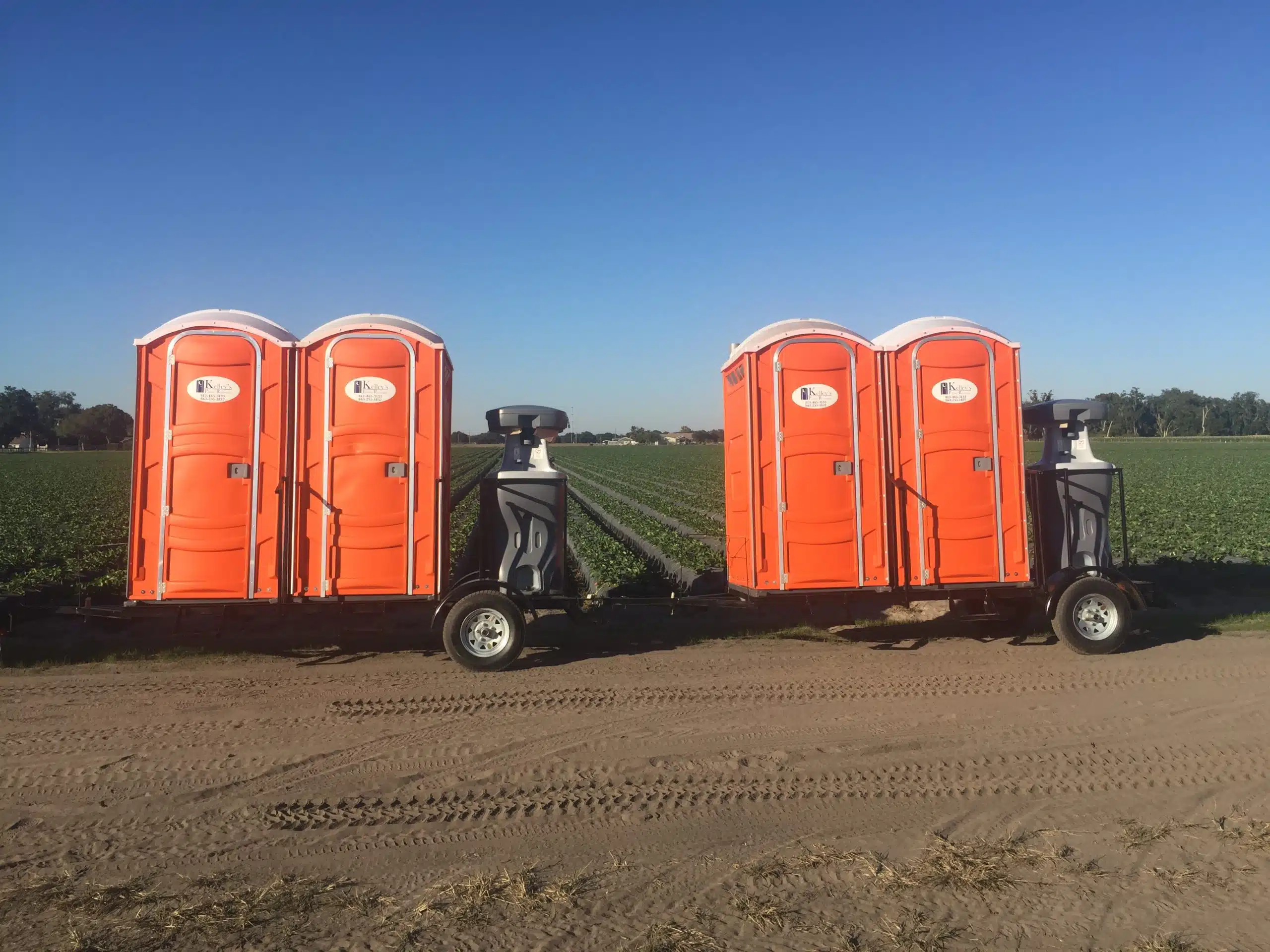 a row of orange portable toilets in a park.