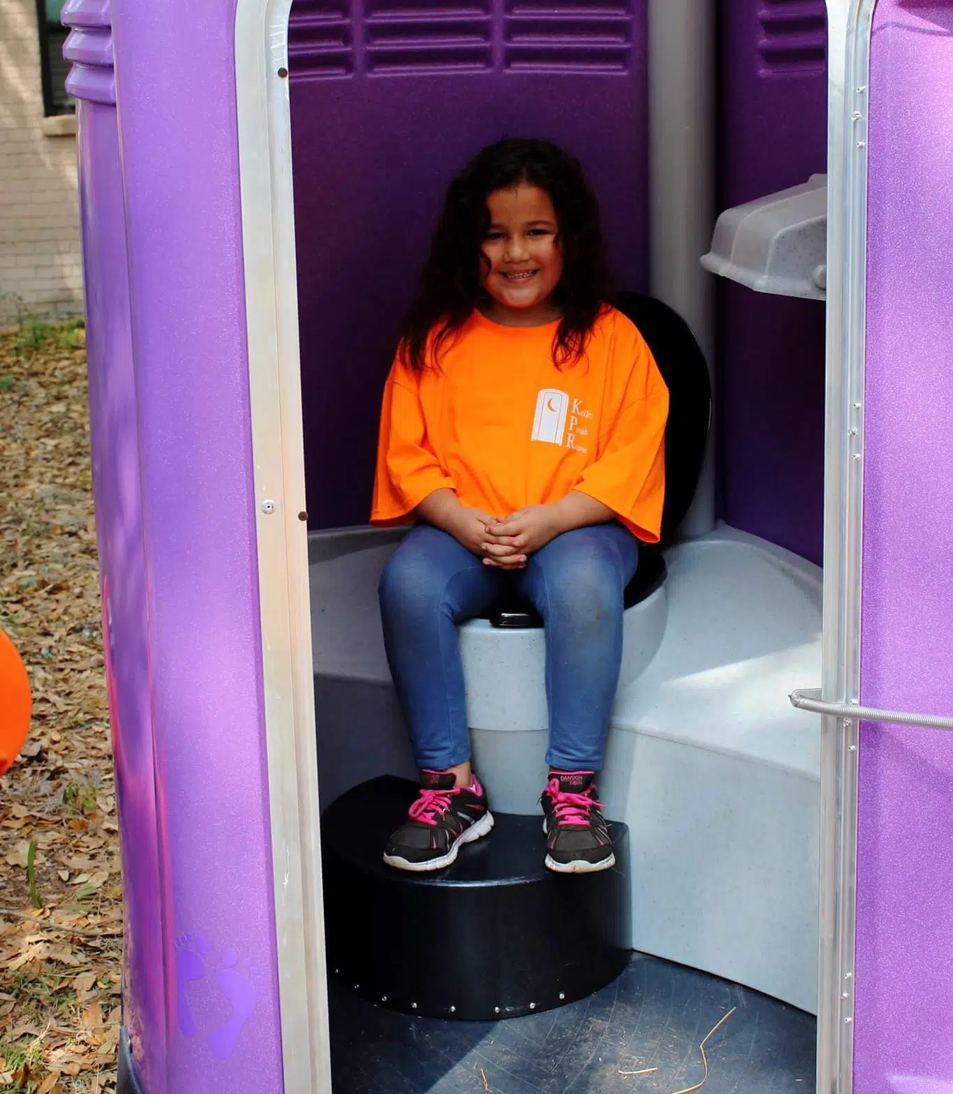 a young girl sitting in a purple and white structure.