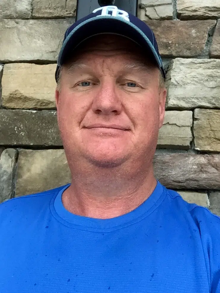 a man in a blue shirt and a baseball cap.